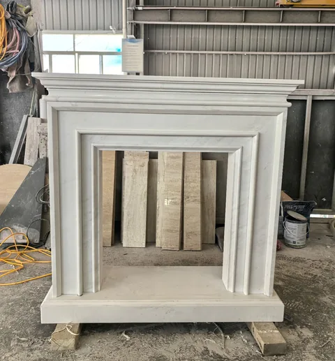 White Volakas marble fireplace surround, with workshop equipment nearby
