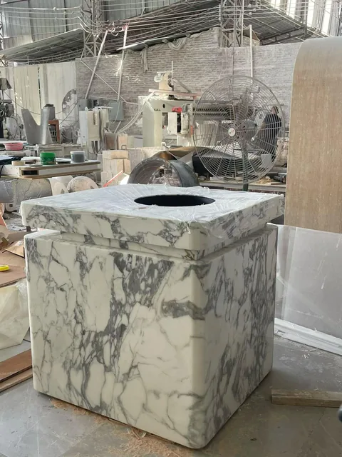 cream-beige stone landscape feature, with bold veining and a reflective finish, in a workshop