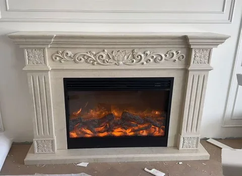 White Volakas marble fireplace surround, with carved scrollwork and a plain surface, in a workshop