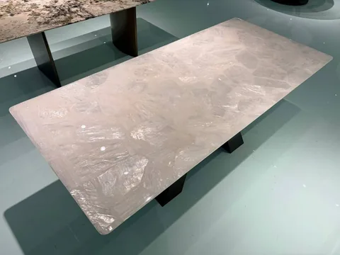cream-beige stone dining table, with a rectangular top and angular breccia fragments, in a showroom