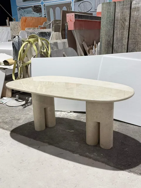 cream-beige stone coffee table, with twin supporting bases and cloudy mottling, in a workshop