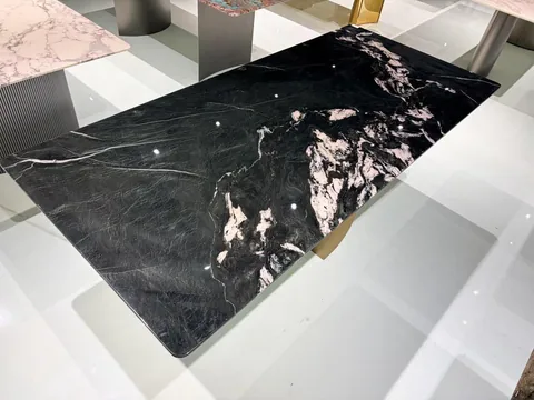 black stone dining table, with a rectangular top and bold veining, in a showroom