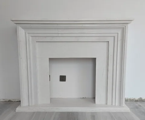 travertine fireplace surround, with stepped tiers and fine veining, on a plain backdrop
