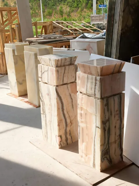 cream-beige stone sink, with a stone pedestal and banded onyx-like striping, in a workshop