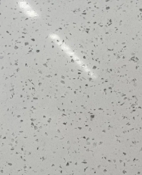 gray engineered stone slab, with a speckled texture and a reflective finish, in a close surface view