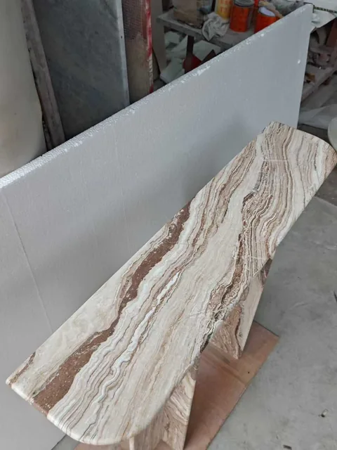 cream-beige stone bench, with a broad slab bench and banded onyx-like striping, in a workshop