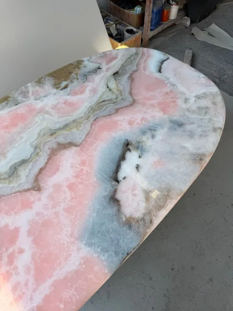 rose-red stone slab, with a single full slab and banded onyx-like striping, in a workshop