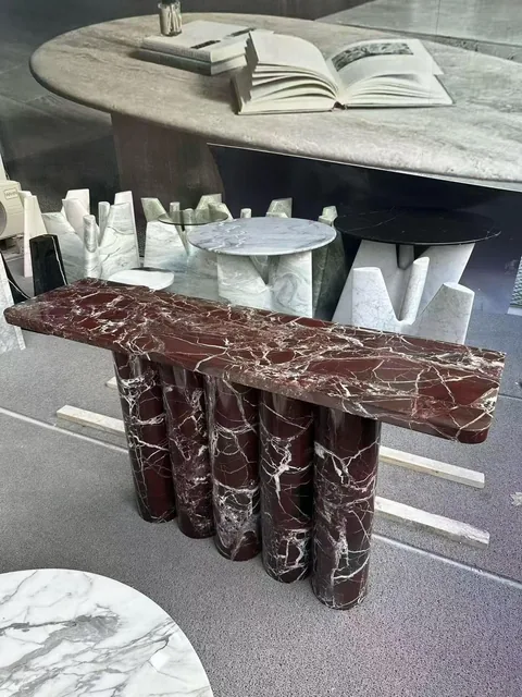 rose-red stone console table, with bold veining and a reflective finish, in a showroom