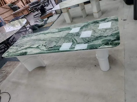 green stone dining table, with twin supporting bases and bold veining, in a workshop