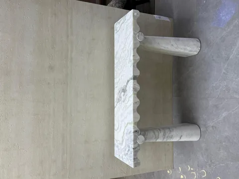 white stone console table, with twin supporting bases and bold veining, in a showroom