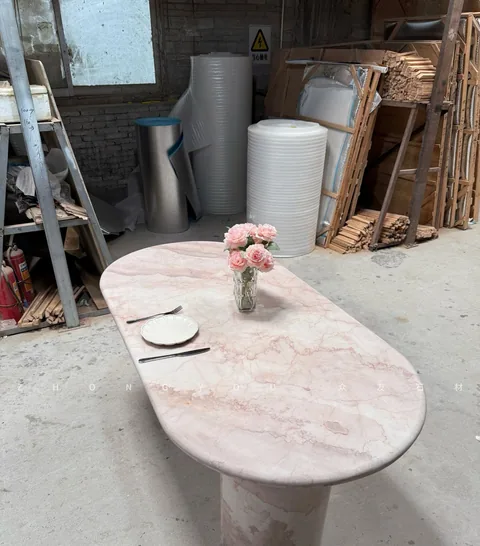 rose-red stone dining table, with fine veining and a reflective finish, in a workshop