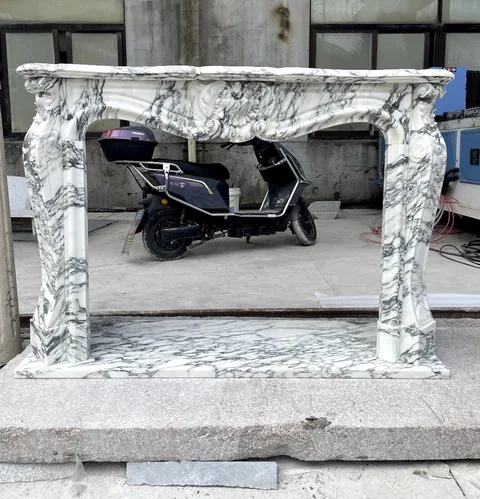 White Volakas marble fireplace surround, with bold veining and workshop equipment nearby