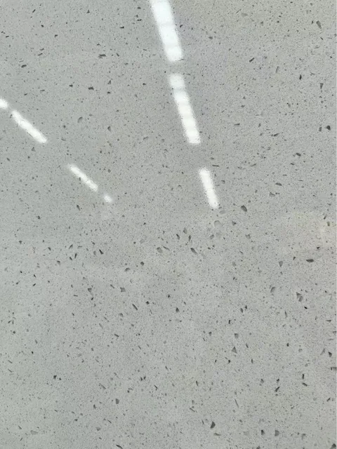 gray engineered stone slab, with a speckled texture and a reflective finish, in a close surface view
