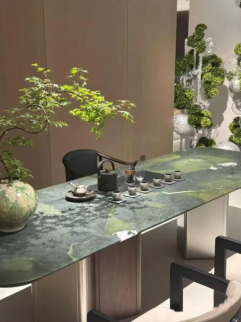 green stone dining table, with twin supporting bases and cloudy mottling, near warm woodwork
