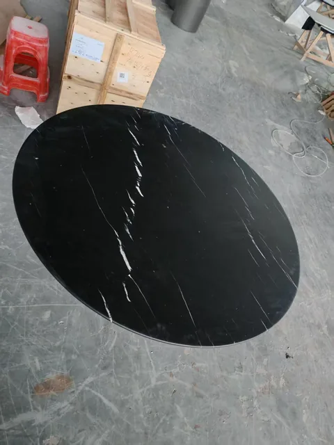 black stone dining table, with an oval top and fine veining, in a workshop
