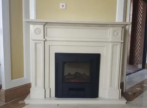 White Volakas marble fireplace surround, with subtle pattern contrast and workshop equipment nearby