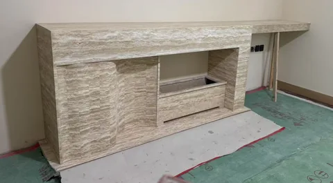 cream-beige stone console table, with linear travertine grain, in a workshop