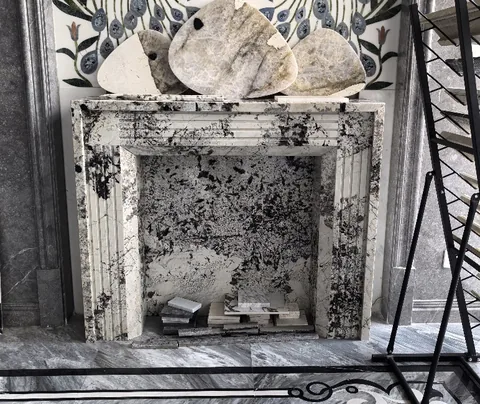 White Volakas marble fireplace surround, with cloudy mottling, in a showroom