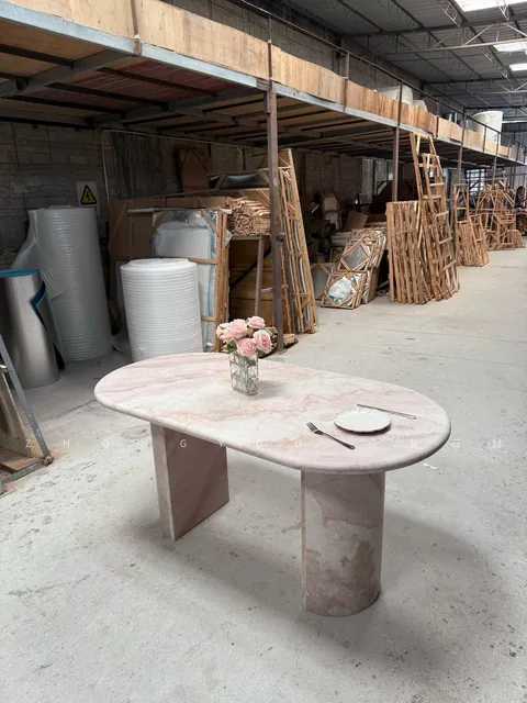 rose-red stone dining table, with twin supporting bases and cloudy mottling, in a workshop