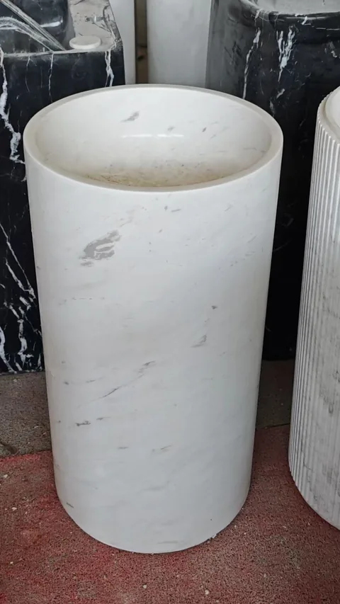 white stone sink, with a form carved from solid stone and fine veining, in a showroom