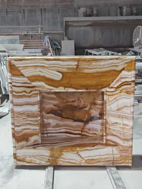 gold stone fireplace surround, with a straight recessed opening and banded onyx-like striping, in a workshop
