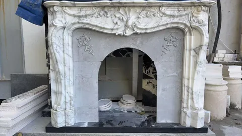White Volakas marble fireplace surround, with fine veining and workshop equipment nearby