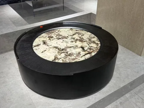 cream-beige stone coffee table, with a round top and bold veining, in a showroom