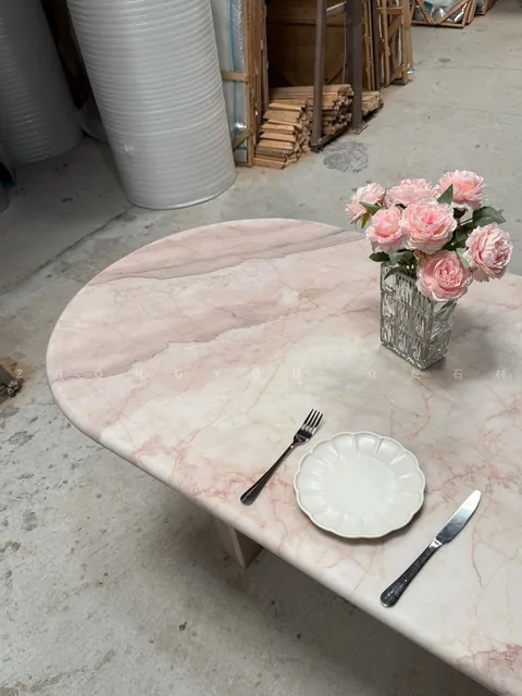 rose-red stone dining table, with fine veining and a reflective finish, in a workshop
