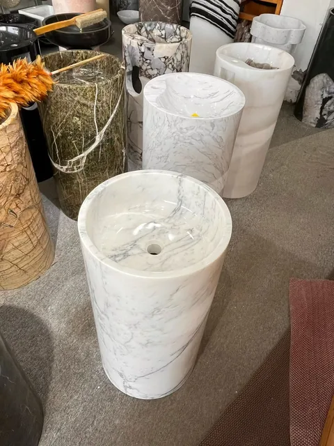 white stone sink, with a form carved from solid stone and fine veining, in a showroom