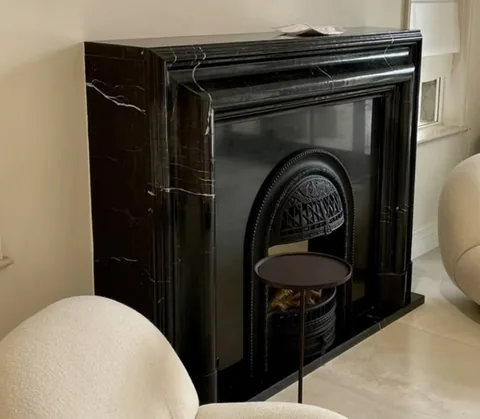 White Volakas marble fireplace surround, with fine veining and a reflective finish, in a furnished room