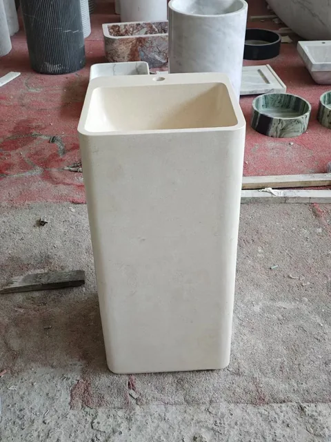 cream-beige stone sink, with a form carved from solid stone and a plain surface, in a workshop