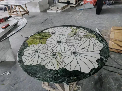green stone dining table, with a round top and bold veining, in a workshop