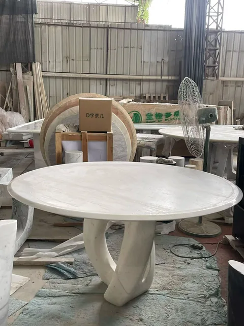 white stone dining table, with subtle pattern contrast and workshop equipment nearby