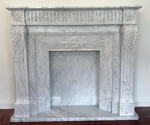 White Volakas marble fireplace surround, with fine veining, on a plain backdrop
