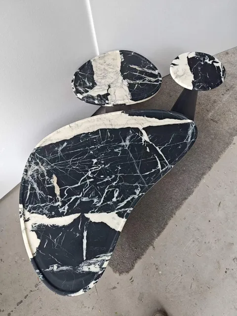 black stone coffee table, with an irregular organic edge and bold veining, in a workshop
