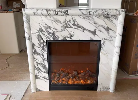Arabescato Corchia marble fireplace surround, with bold veining and a reflective finish, in a workshop