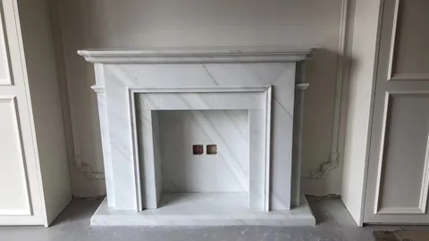 Arabescato Corchia marble fireplace surround, with fine veining, against a pale background