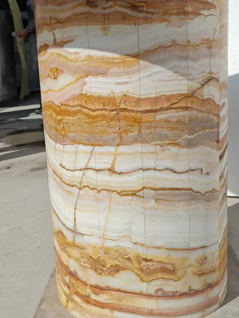 cream-beige stone slab, with banded onyx-like striping and a reflective finish, outdoors