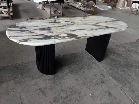 white stone dining table, with bold veining and workshop equipment nearby