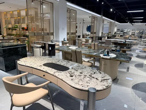 cream-beige stone dining table, with bold veining and a reflective finish, in a showroom