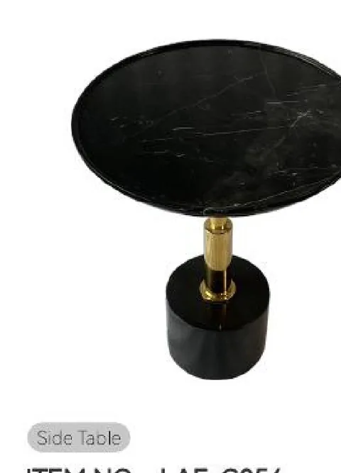 black stone side table, with a round top and fine veining, on a plain backdrop