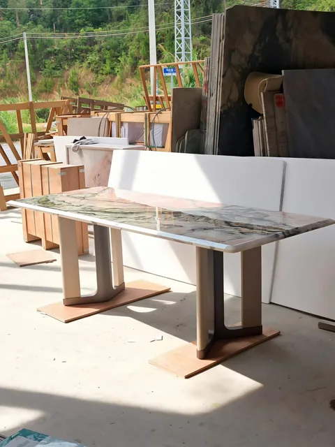cream-beige stone dining table, with twin supporting bases and bold veining, in a workshop