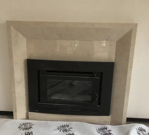 White Volakas marble fireplace surround, with cloudy mottling, in a furnished room