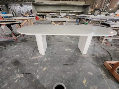 white stone dining table, with fine veining and workshop equipment nearby