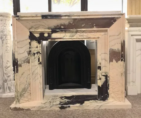 White Volakas marble fireplace surround, with stepped tiers and bold veining, in a showroom