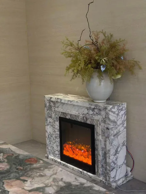 white stone fireplace surround, with stepped tiers and bold veining, in a showroom