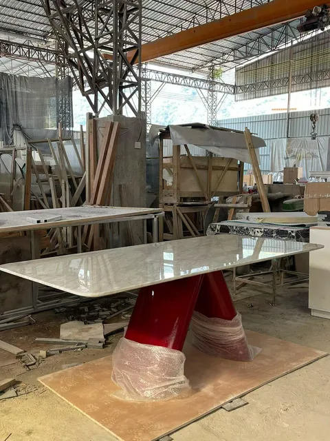 cream-beige stone dining table, with fine veining and a reflective finish, in a workshop
