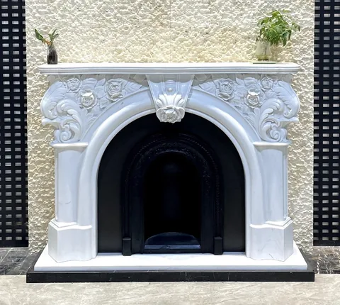 White Volakas marble fireplace surround, with an arched opening and fine veining, in a showroom