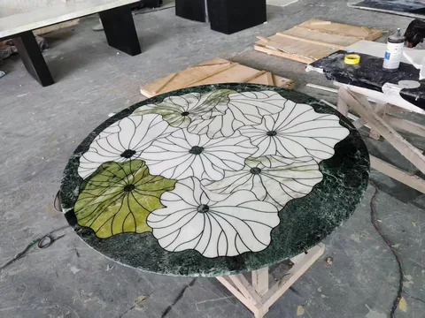 green stone coffee table, with a round top and cloudy mottling, in a workshop