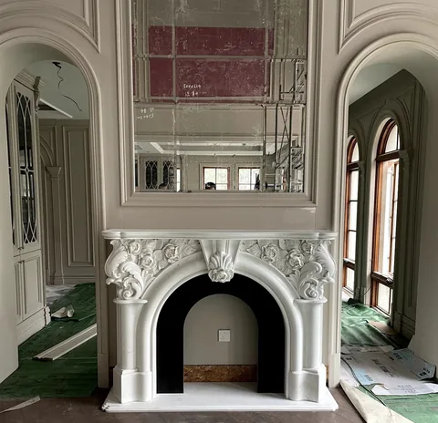 White Volakas marble fireplace surround, with subtle pattern contrast and workshop equipment nearby